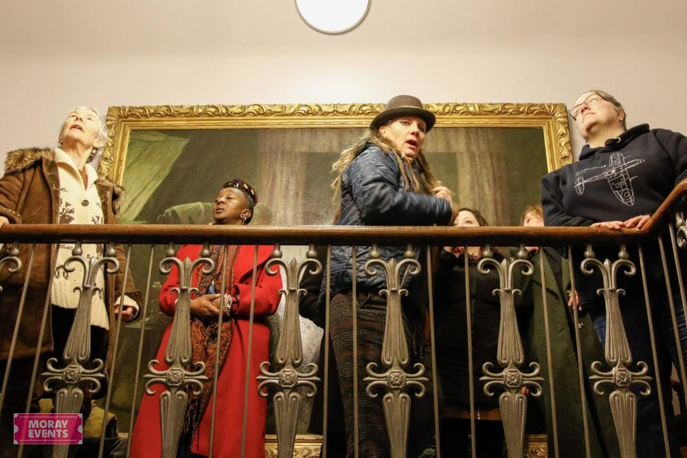 Vibrant group of people enjoying an art exhibition at Moray Events, showcasing the local culture and diverse attendees in a historic gallery setting.