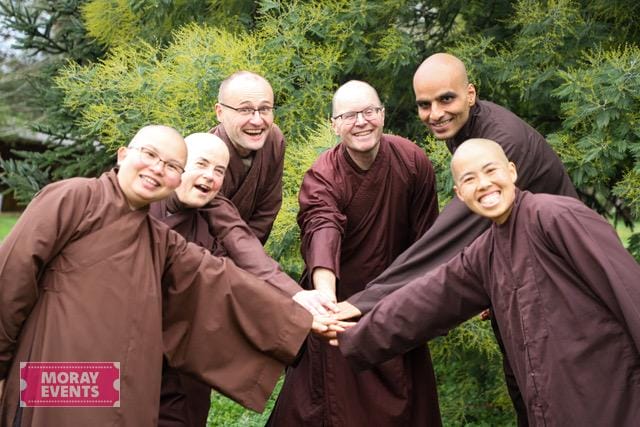Moray Events team in traditional brown robes participating in a team-building outdoor activity in a lush green setting.
