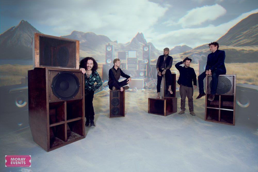 Large audio speakers with band members performing in a surreal mountainous landscape setting for Moray Events.