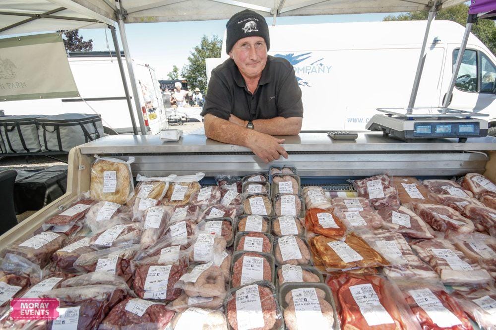 High-quality fresh meat stall at Moray Events market, featuring a variety of meats displayed on ice with an experienced butcher vendor.