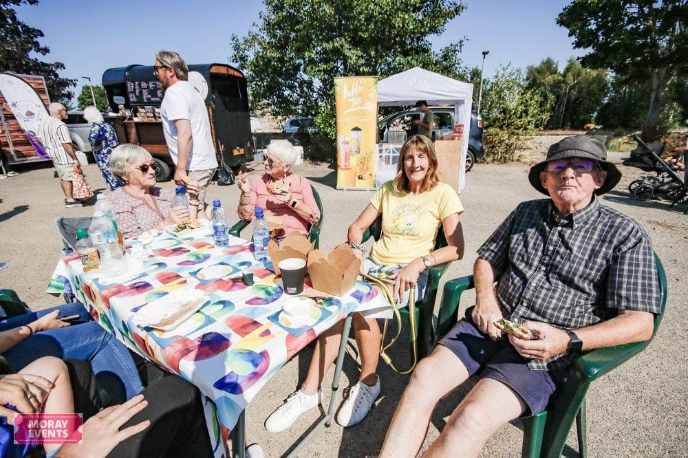 Festival outdoor event Moray Events, community gathering, live food and music, family friendly atmosphere, sunny day, relaxed socialising in Moray.