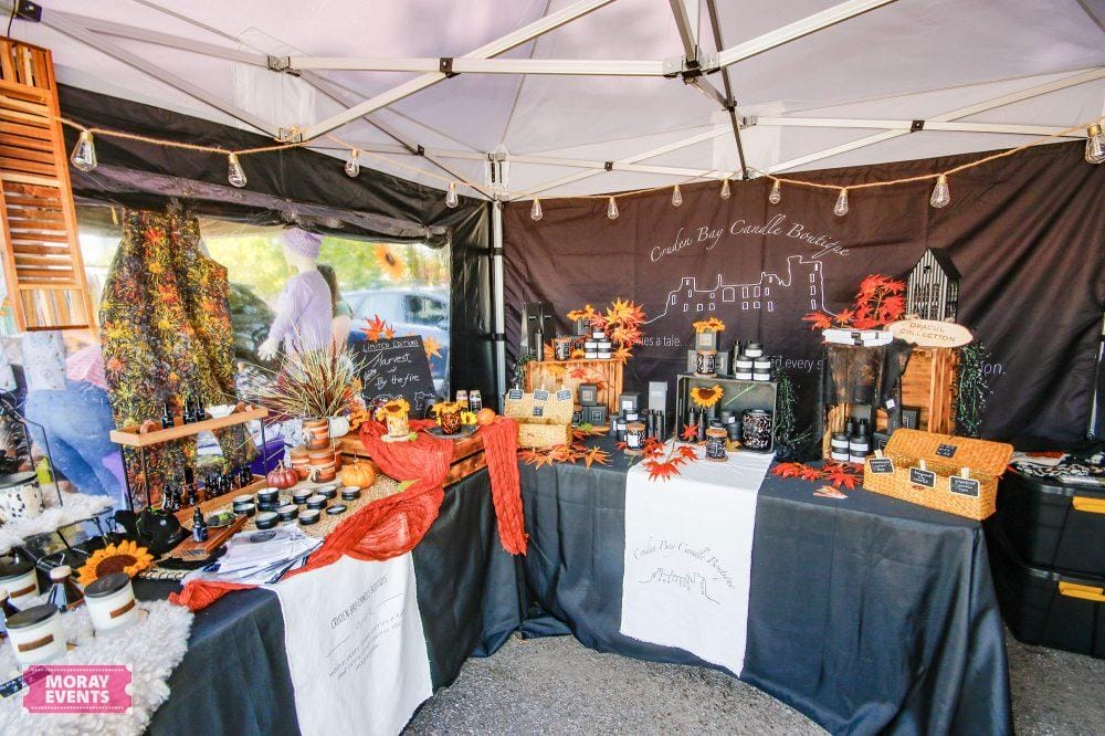 Colourful craft market stall at Moray Events showcasing autumn-themed candles, pumpkins, and local handmade products in a festive outdoor setting.